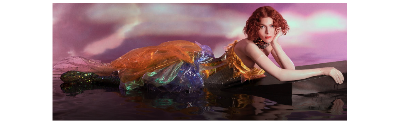 Sophie lies against a purple backdrop in a translucent lilac and orange dress.