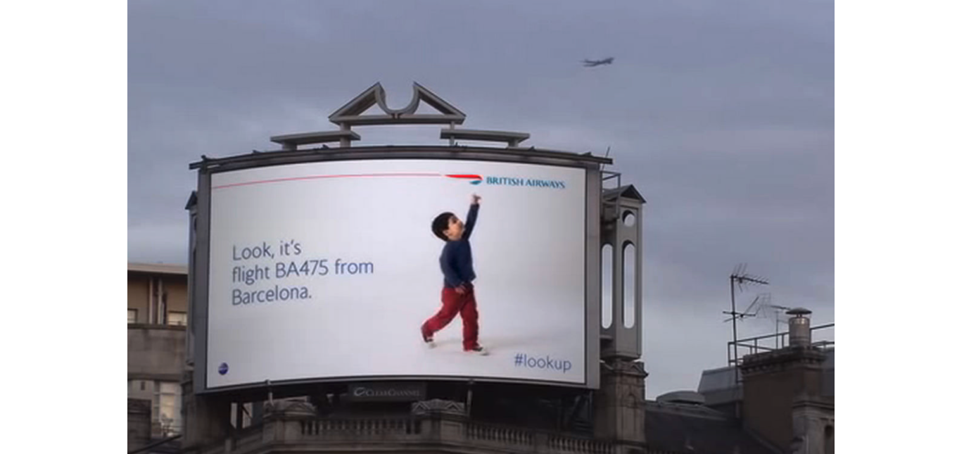 Young child points at sky on billboard, matched with flight data. The plane flies overhead. 