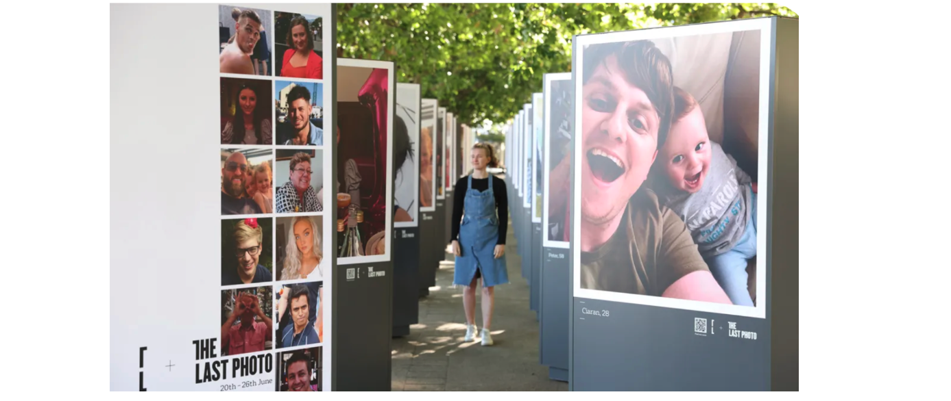 Woman walks through an exhibition showing the last photos of people who committed suicide in June of the year of the campaign. 