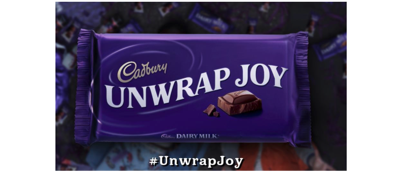 Cadbury’s chocolate bar sits in purple wrapper, it reads: Unwrap Joy.
