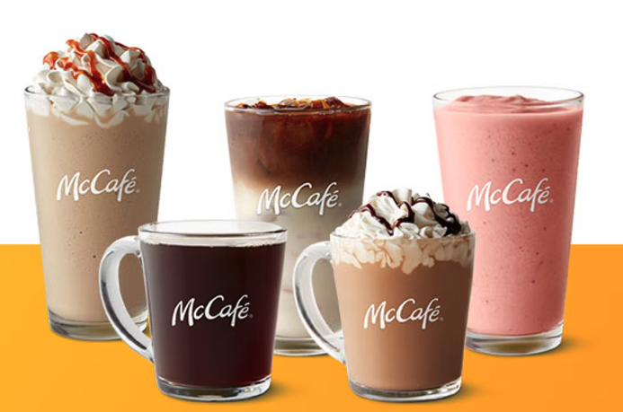Assorted McDonald’s McCafé beverages in a line against brand color background