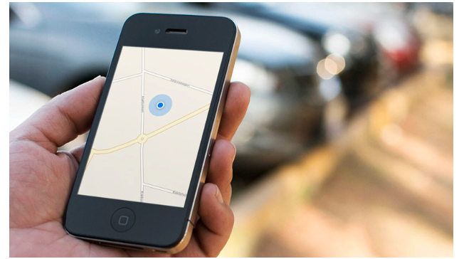 a white person’s hand holding a phone with the image of a map with a blue dot on it 