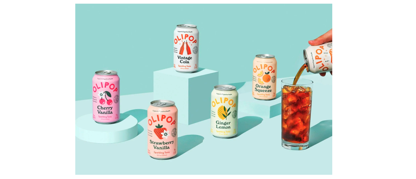 Colorful cans and a glass of Olipop sit on a blue table, against a blue backdrop in the same shade.