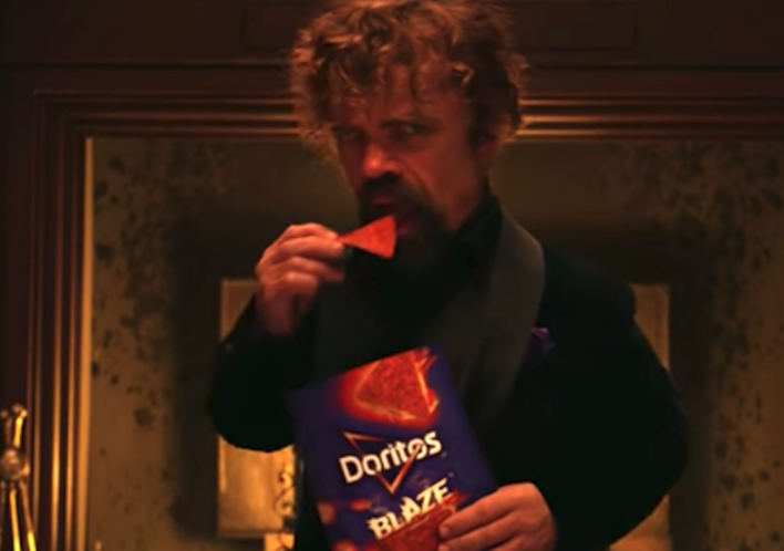 Peter Dinkaridge features in Super Bowl Commercial with a bag of Blaze Doritos, against a fireplace.