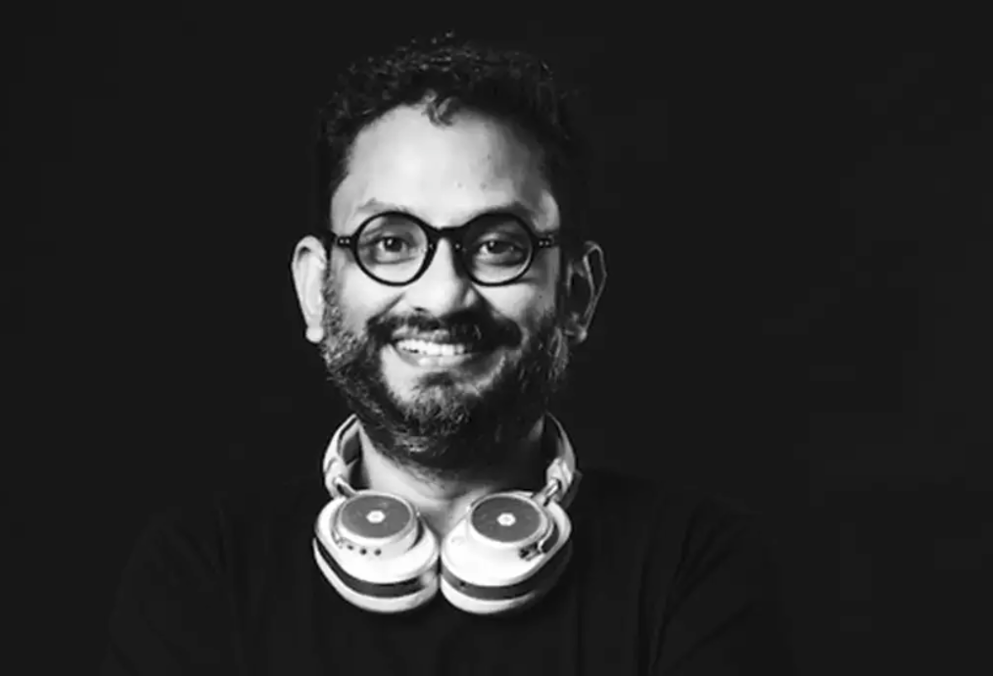 Rajdeepak Das smiling with headphones around his neck. 