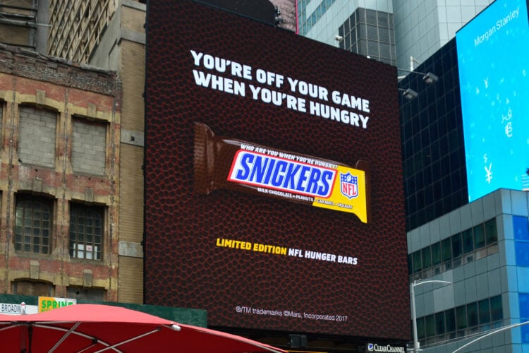 Photo of a Snickers ad across a building that is football themed